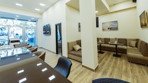 A spacious room with a large table, several sofas, and a view through a glass door. - L'image Art Hotel (Yerevan)