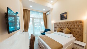 A hotel room with a large bed, a TV mounted on the wall, a window with curtains, and a picture on the wall. - L'image Art Hotel (Yerevan)
