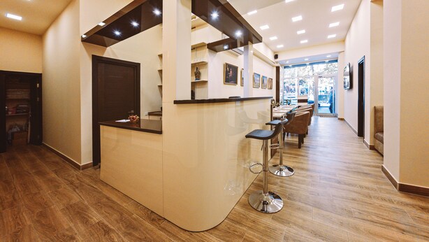 A reception area with a counter, bar stools, and a view into the dining area. - L'image Art Hotel (Yerevan)