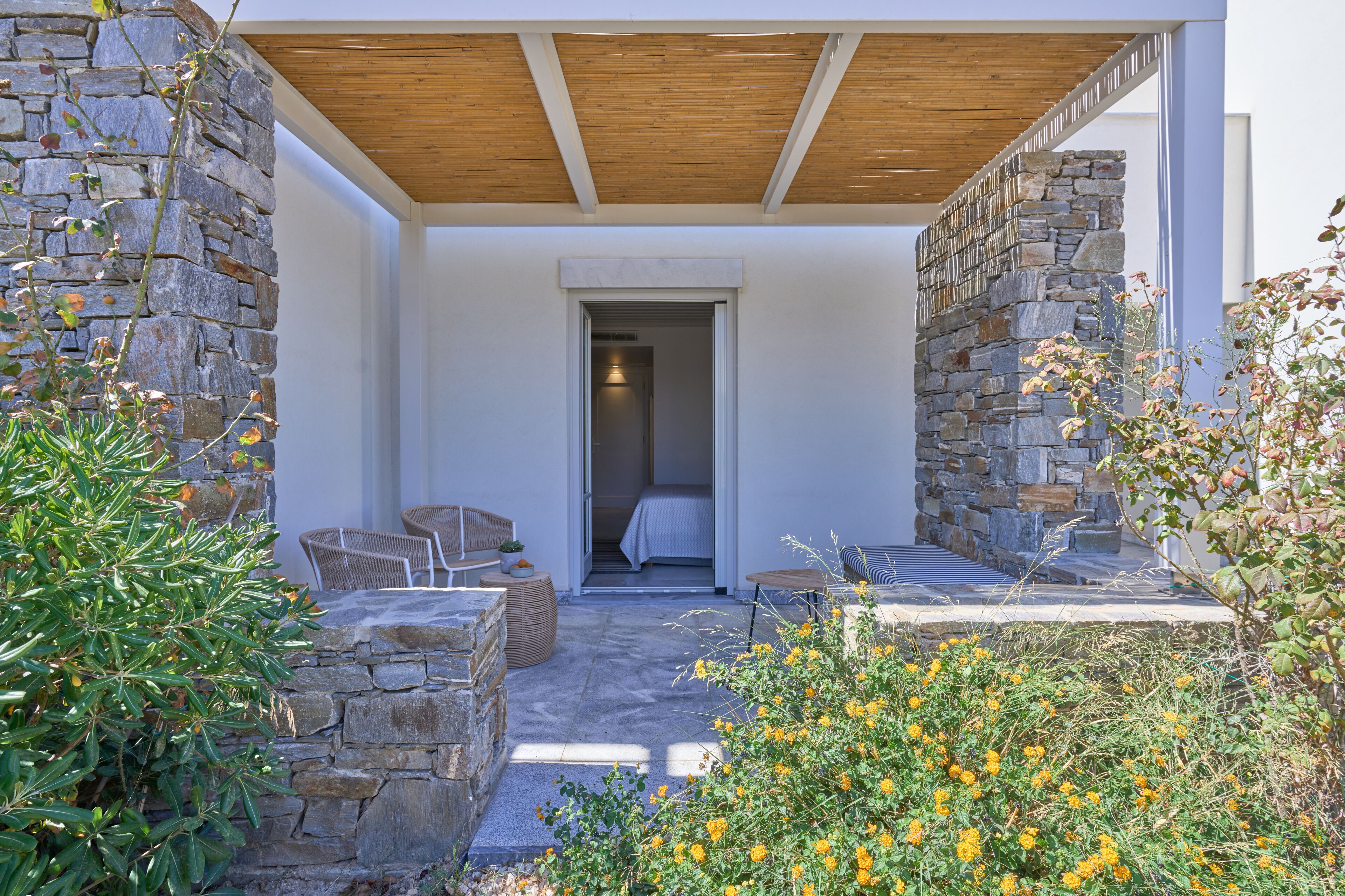 Patio in pietra con sedute all'aperto, tetto in legno e vista su una stanza con un letto.