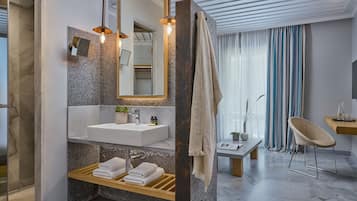 Une salle de bain moderne avec un lavabo en marbre, un miroir, un porte-serviettes et un espace douche.