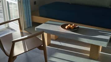 A modern room with a blue sofa, a wooden chair, and a table with a bowl of fruit.
