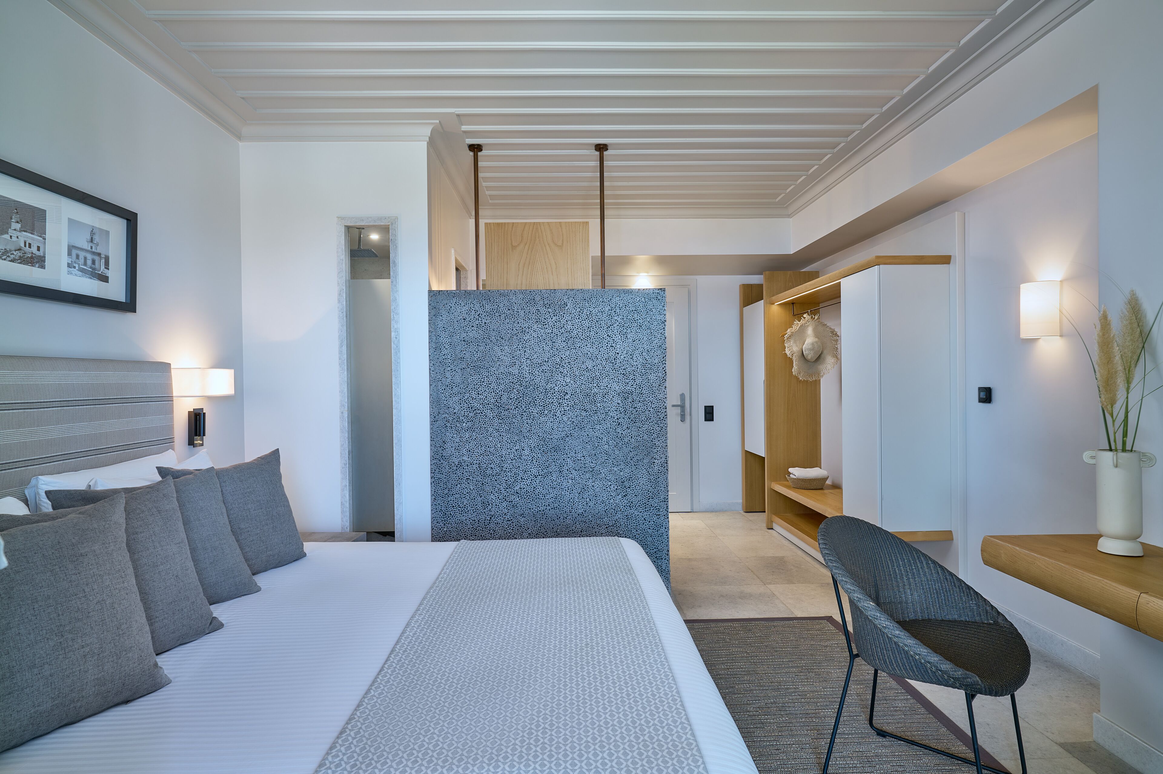 Une chambre d’hôtel moderne, dotée d’un grand lit, d’une chaise, d’une petite table et d’un luminaire fixé au mur.