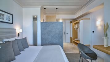 Une chambre d’hôtel moderne, dotée d’un grand lit, d’une chaise, d’une petite table et d’un luminaire fixé au mur.