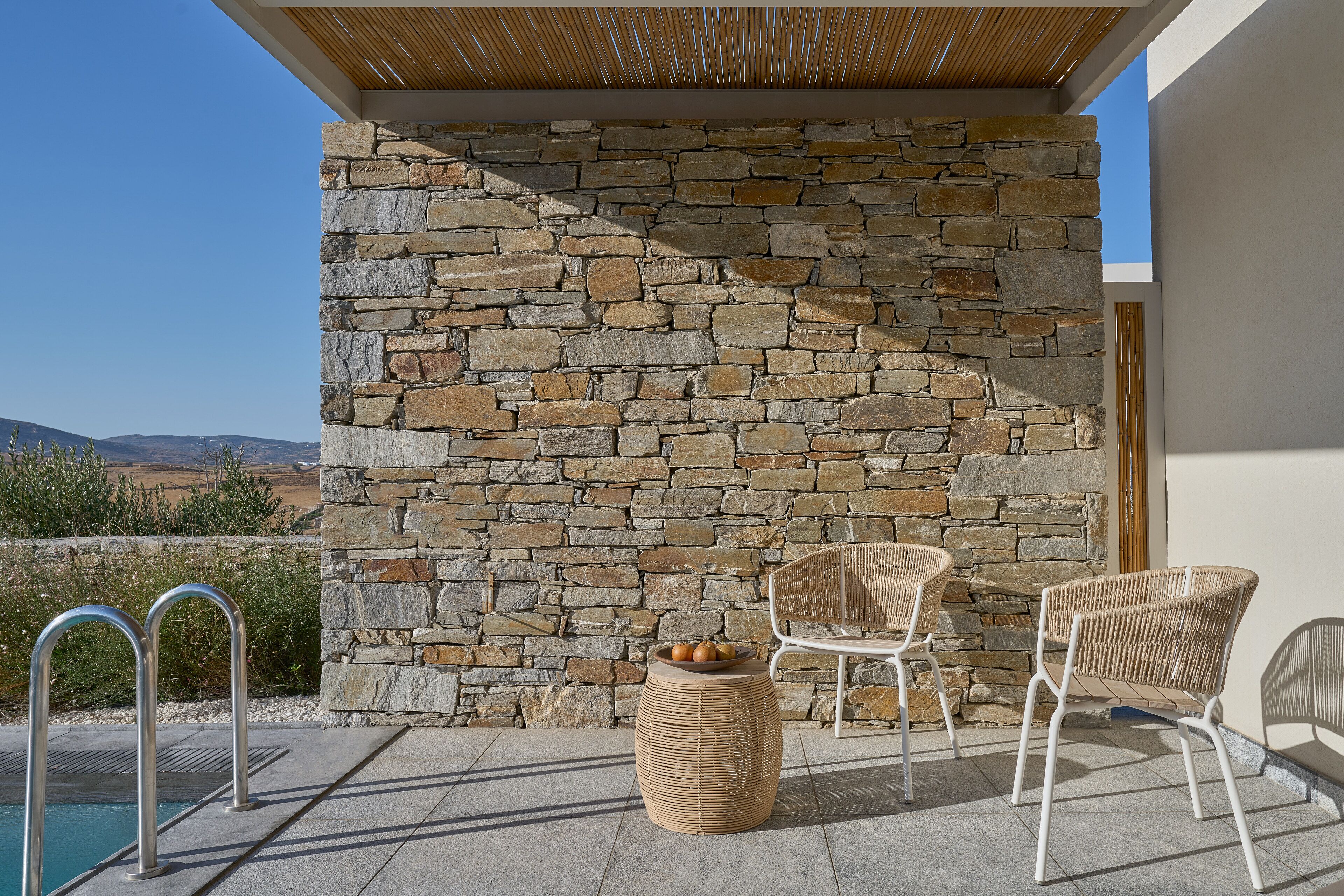A stone wall, outdoor seating, and a pool.