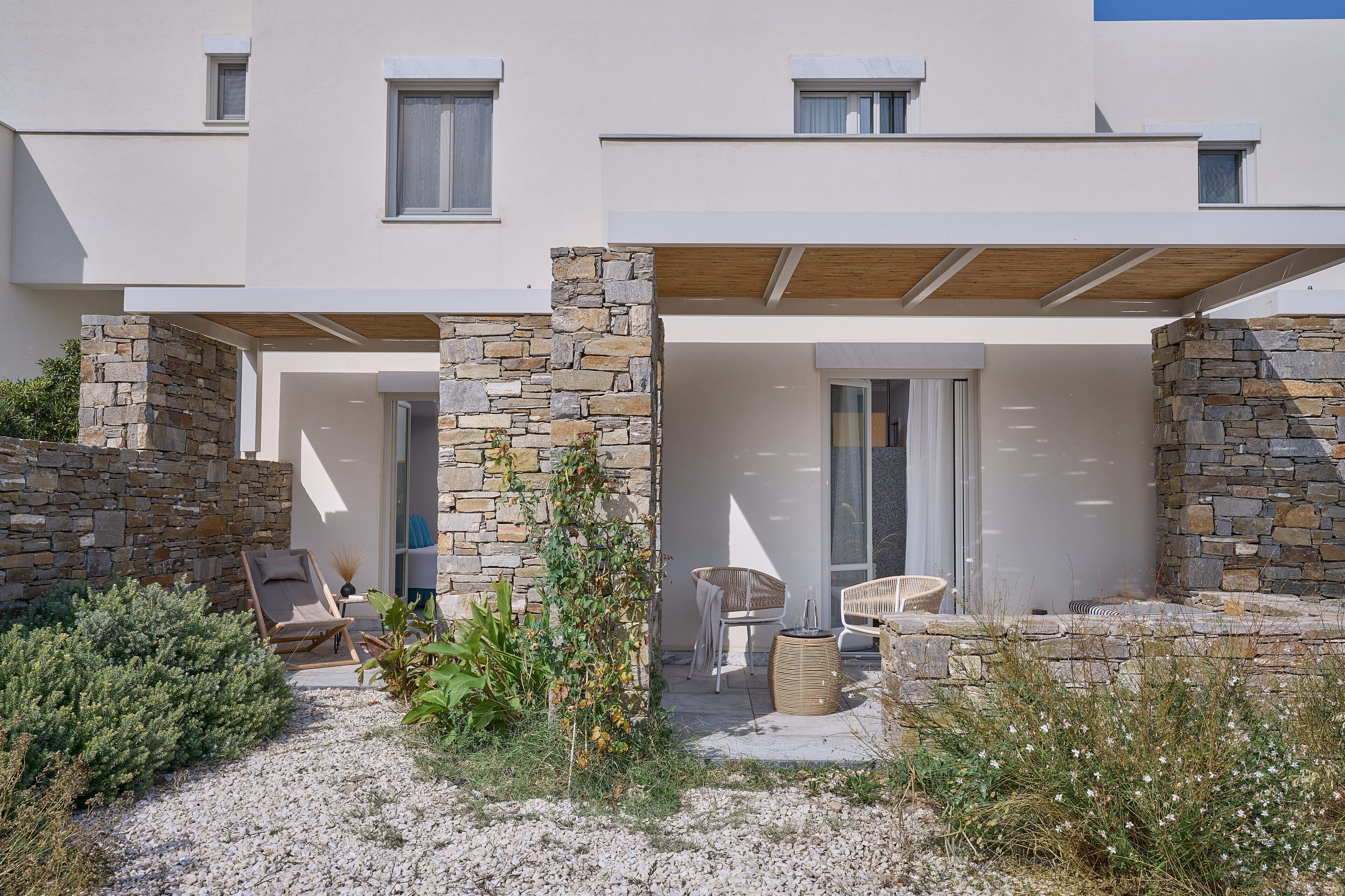 A modern building with a stone facade, outdoor seating, and a covered patio area.