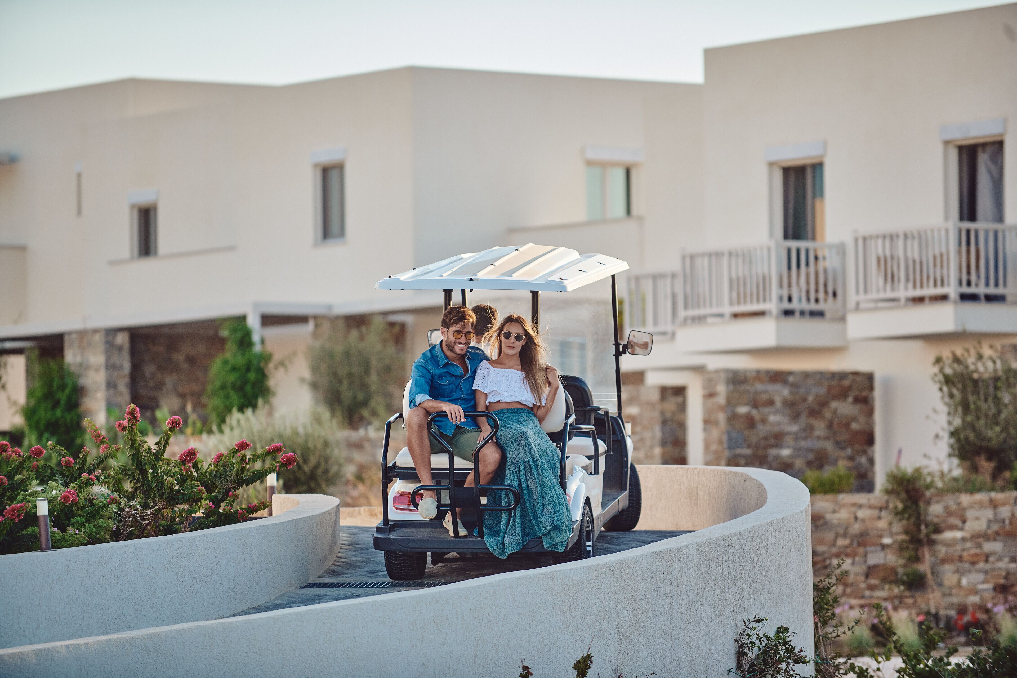 A couple on a golf cart with a modern building in the background.