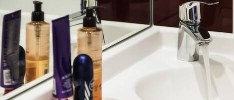 Un lavabo de salle de bain avec un miroir, un robinet et divers produits de toilette.