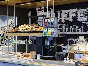 Mostrador de panadería con pan, pasteles y una máquina de café.