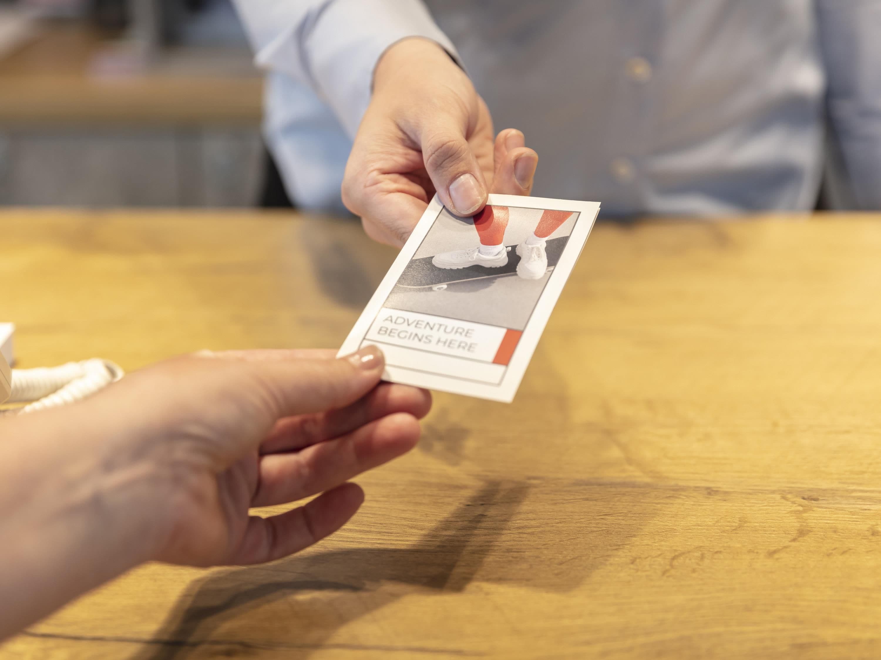 A person handing over a card with a photo and text to another person.