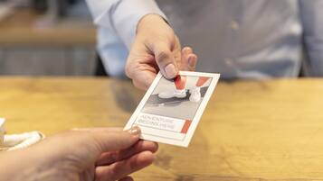 A person handing over a card with a photo and text to another person.