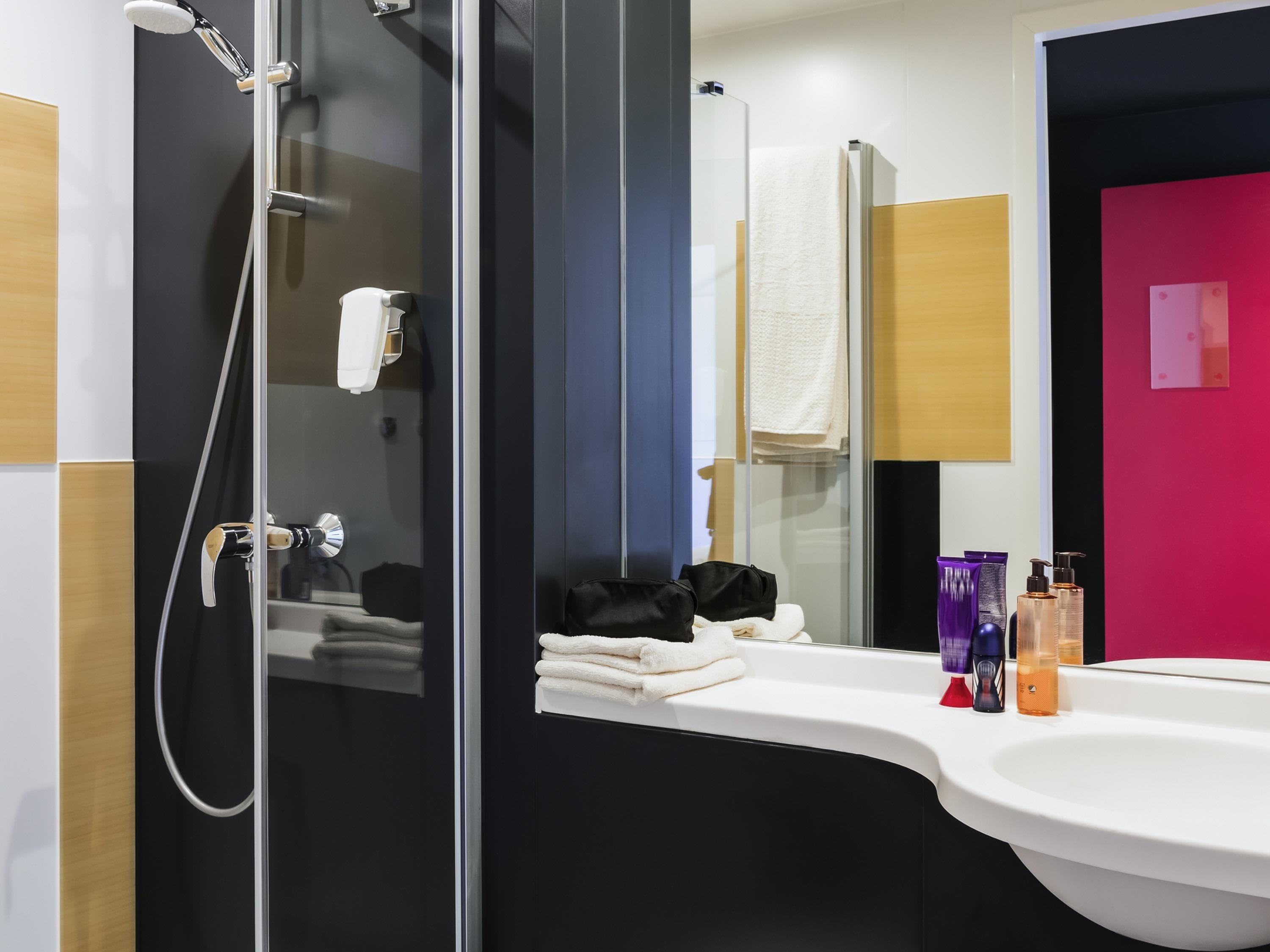 A modern bathroom with a glass shower enclosure, a white sink, and a mirror.