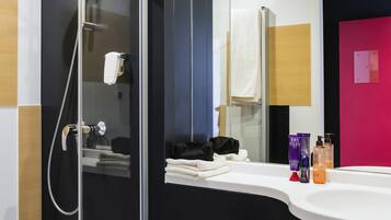 A modern bathroom with a glass shower enclosure, a white sink, and a mirror.