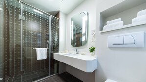 A modern bathroom with a glass shower enclosure, a white sink with a mirror, and a toilet. - ibis Yixing South Renmin Rd (Wuxi)