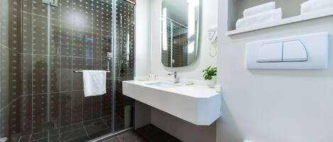 A modern bathroom with a glass shower enclosure, a white sink with a mirror, and a toilet.