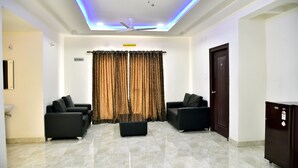 A modern living room with two black sofas, a glass coffee table, and a ceiling fan. - Sapphire Asta (Hyderabad)
