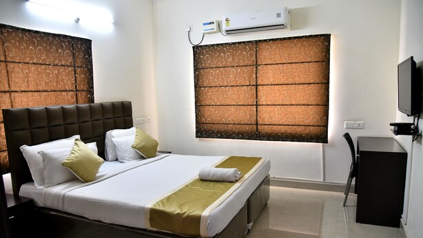 A hotel room with a large bed, a desk, and a television. - Sapphire Asta (Hyderabad)