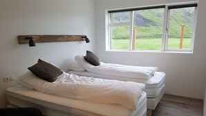 Una habitación con dos camas, un banco de madera y una ventana que ofrece vistas a un paisaje verde.