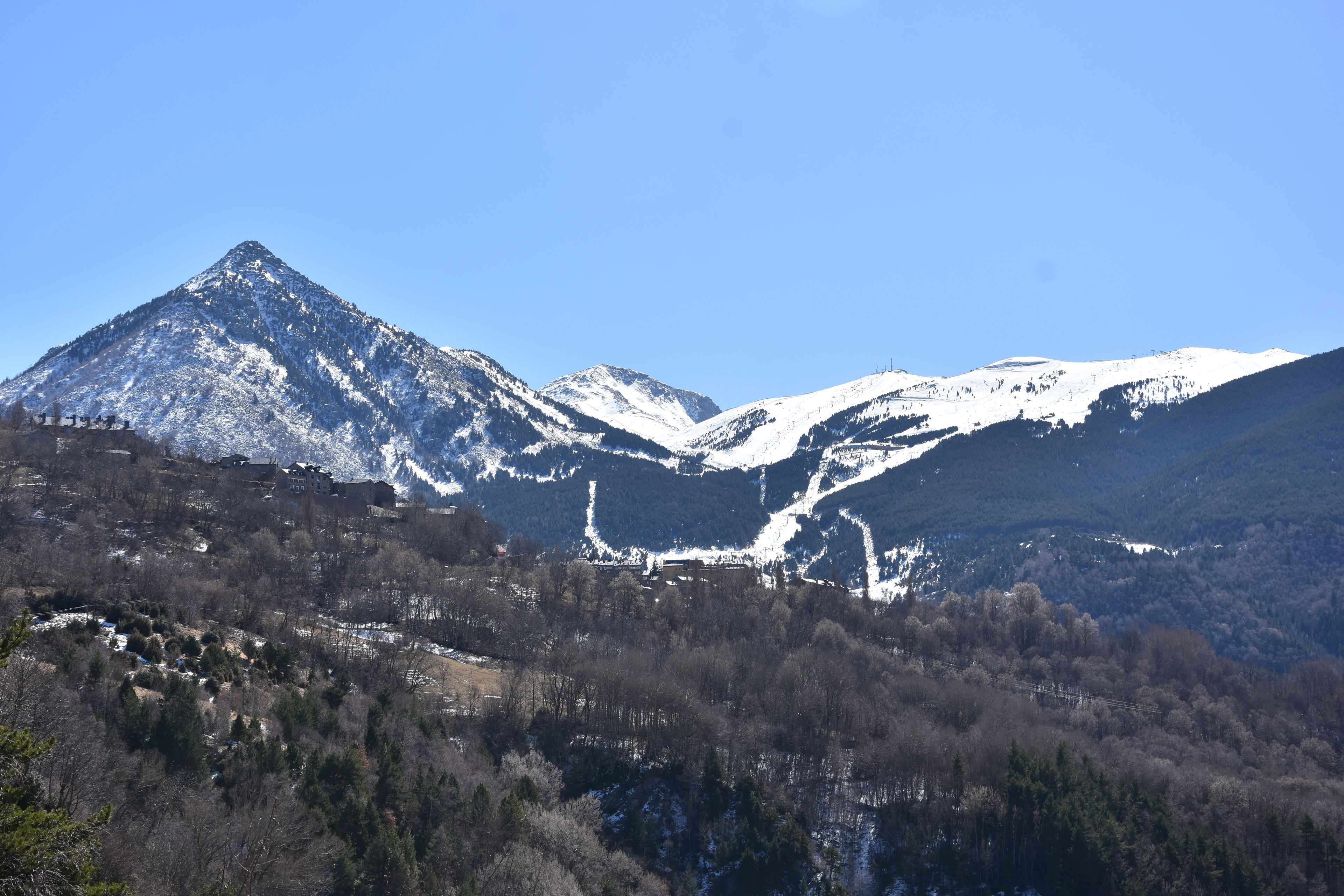 A mountainous landscape with snow-capped peaks and a valley with sparse vegetation.