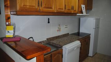 A kitchen with wooden cabinets, a granite countertop, a white dishwasher, and a small sink.
