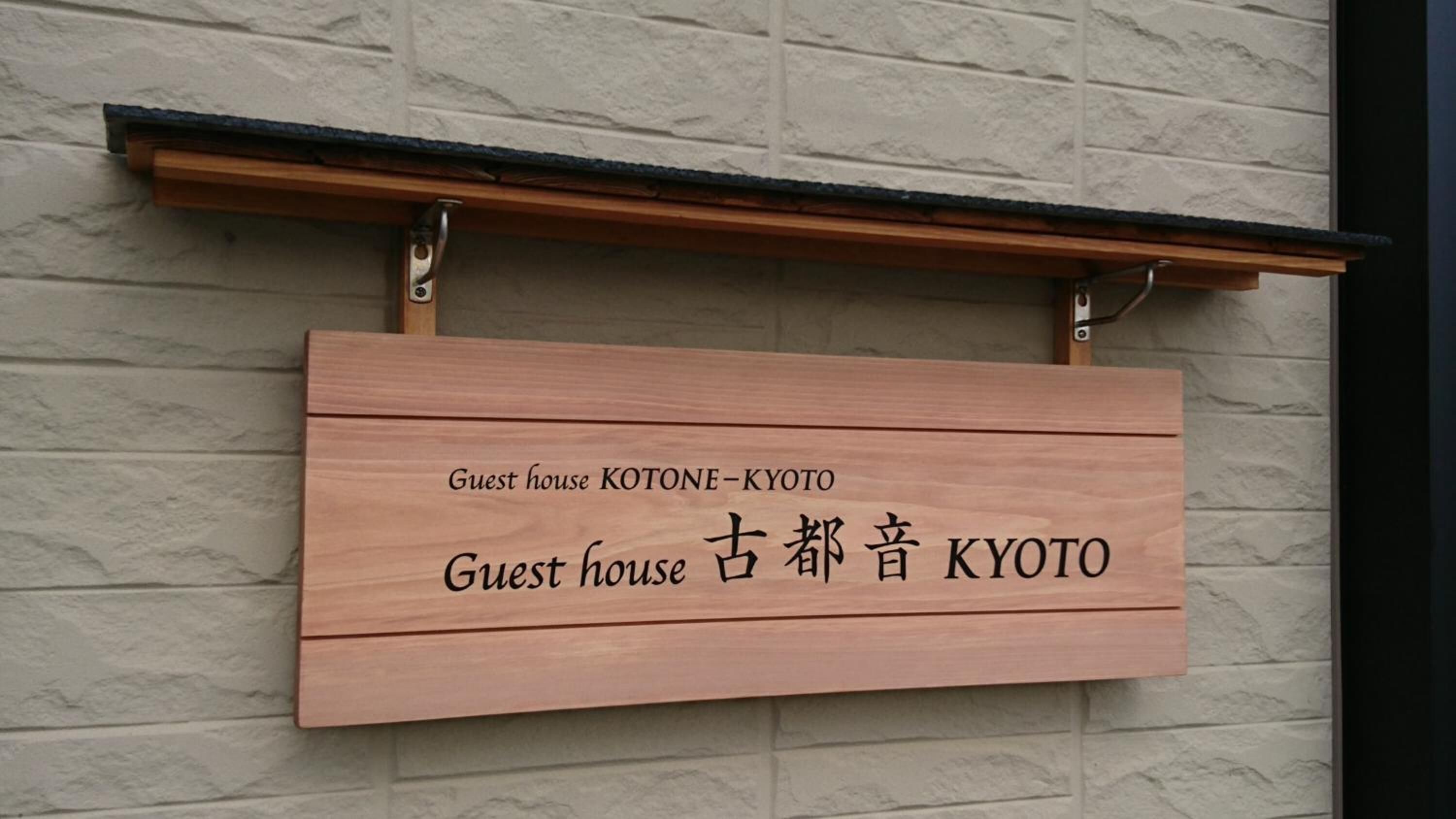 A wooden sign with "Guest house KOTONE-KYOTO" and "Guest house KYOTO" written in English and Japanese.
