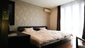 A modern bedroom with a patterned wall, a bed with a beige bedspread, a nightstand, and a wall-mounted air conditioner. - Guest house KOTONE KYOTO (Kyoto)