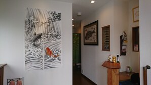 A hallway with a large artwork depicting koi fish and waves, a framed picture of a fish, and a small wooden table with decorative items. - Guest house KOTONE KYOTO (Kyoto)