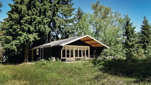 A log cabin with a wooden roof and large windows, surrounded by tall trees and a grassy area. - Nice home in Månsarp with kitchen (Månsarp)