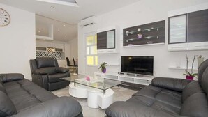 A modern living room with leather sofas, a glass coffee table, a flat-screen TV, and minimalist decor. - Apartments Paradis (Rovinj)