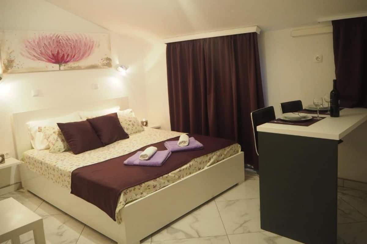 A bedroom with a bed, a desk, and a painting on the wall.