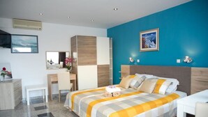 A modern hotel room with a large bed, a desk, and a chair. - Apartments Paradis (Rovinj)