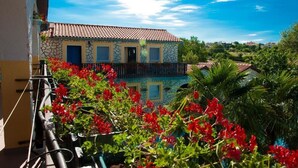 A two-story building with a tiled roof, a balcony with red flowers, and a view of the surrounding landscape. - Apartments Paradis (Rovinj)