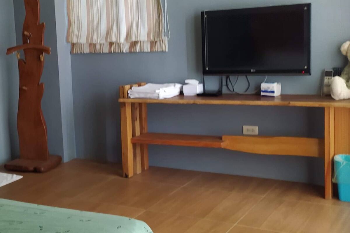 Una habitación con un banco de madera, un televisor y una cortina a rayas.