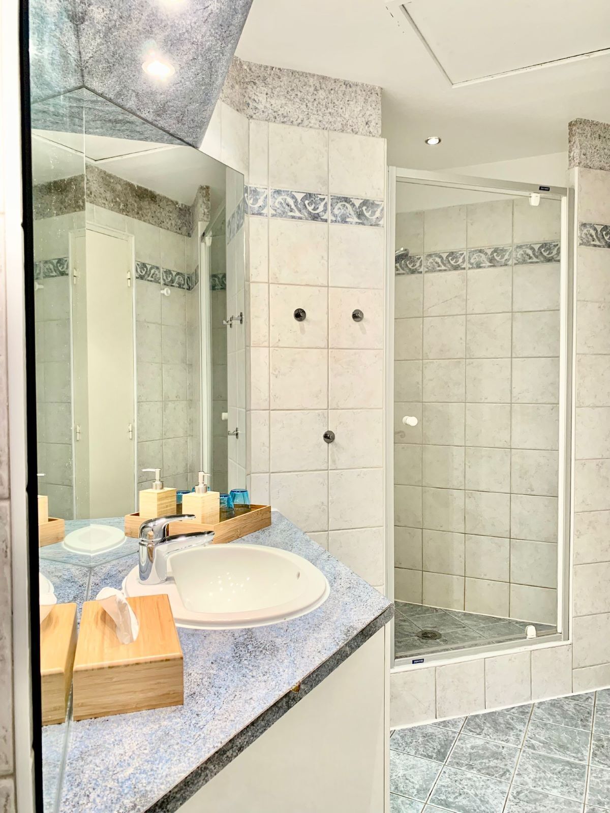 Un baño con lavamanos, espejo y ducha.