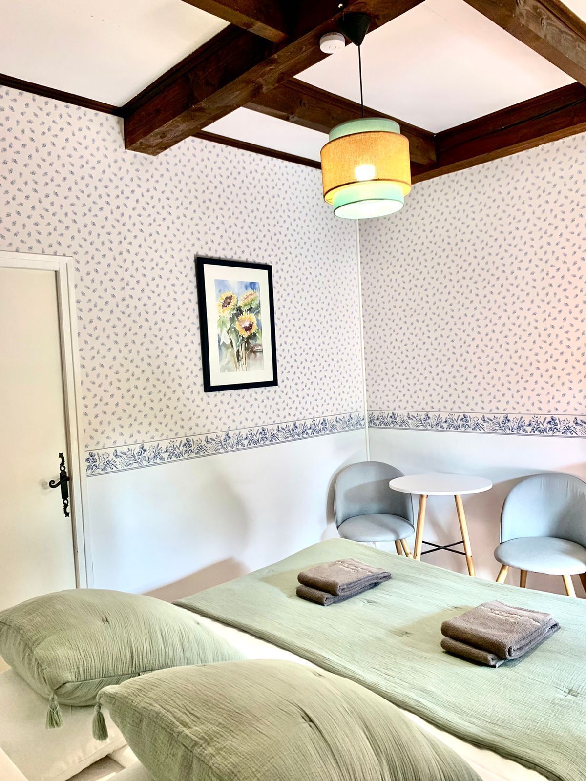 Un dormitorio con una cama, dos sillas, una mesa y una lámpara en el techo.