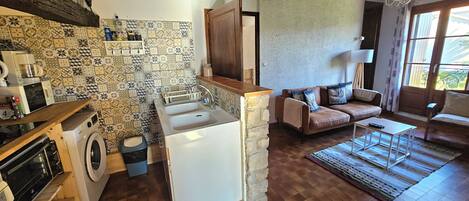 A compact kitchen with a washing machine, a sink, and a wooden countertop.