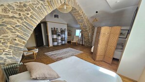 Une chambre avec une arche en pierre, un lit avec des oreillers, un plancher en bois et une cloison en osier.