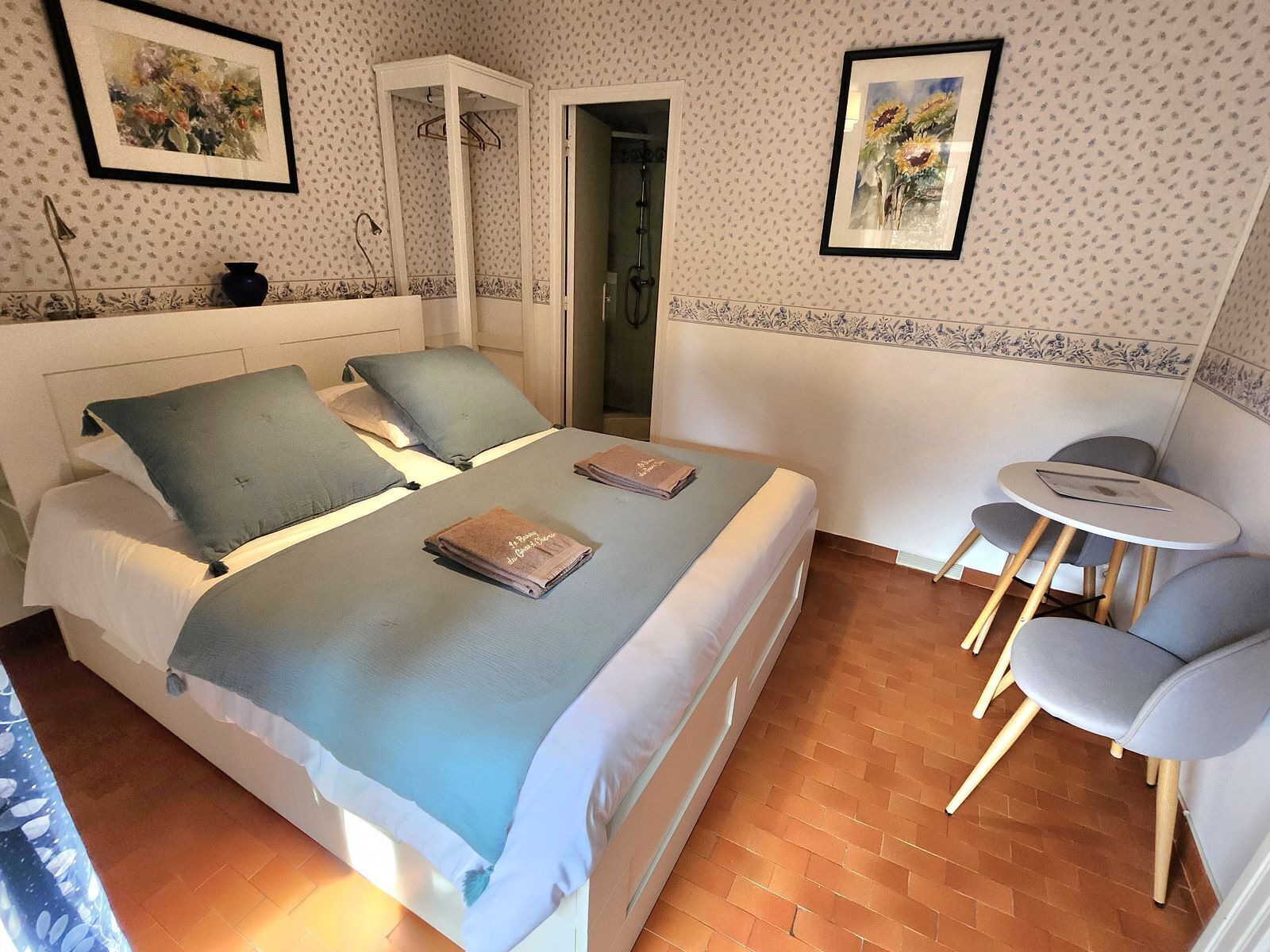 Une chambre à coucher avec un lit, deux oreillers, une table de chevet, une chaise et une petite table sur laquelle se trouve un livre.