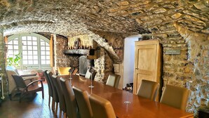 Un coin repas rustique avec un mur en pierre, une table en bois et des chaises en cuir.