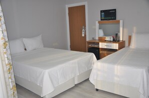 A hotel room with two beds, a desk with a television, and a coffee maker.