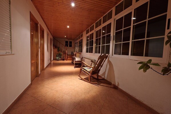Un couloir doté d’un plancher en bois, de grandes fenêtres et d’un fauteuil à bascule.
