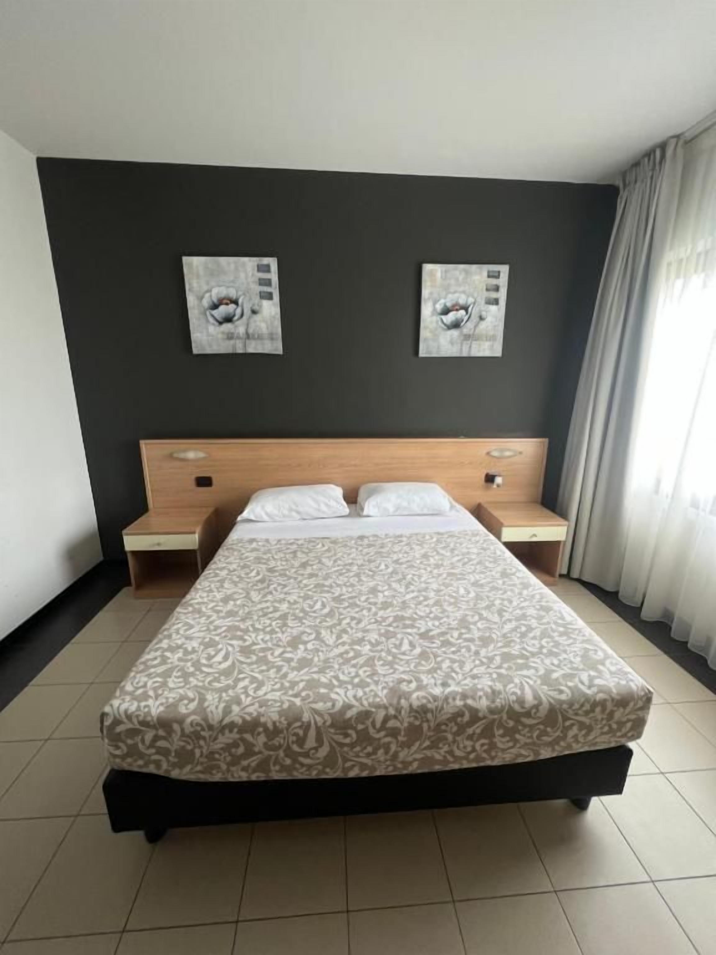 Une chambre d’hôtel avec un grand lit, deux tables de chevet et des œuvres d’art accrochées au mur.