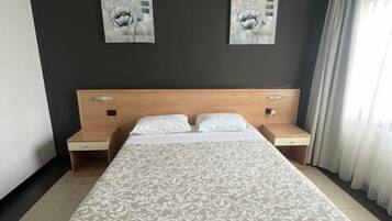 Une chambre d’hôtel avec un grand lit, deux tables de chevet et des œuvres d’art accrochées au mur.