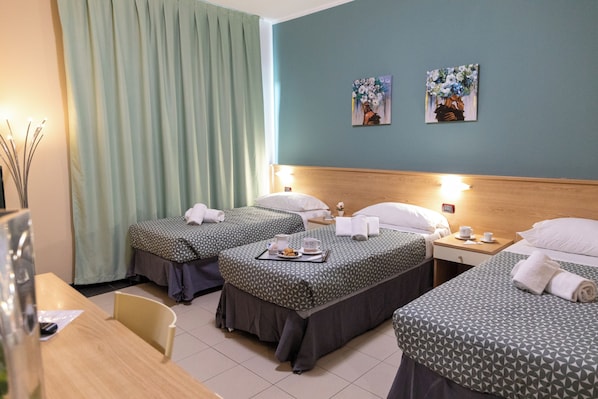 Habitación de hotel con dos camas individuales, cabecero de madera, una mesita con bandeja y una silla.