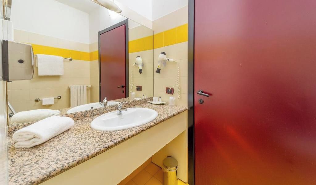 Een badkamer met twee wastafels, een spiegel en een rode deur.