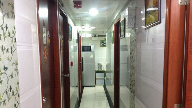 A narrow hallway with wooden doors on either side, a refrigerator, and a small table with a chair in the center. - Head Sun Guest House (Kowloon)