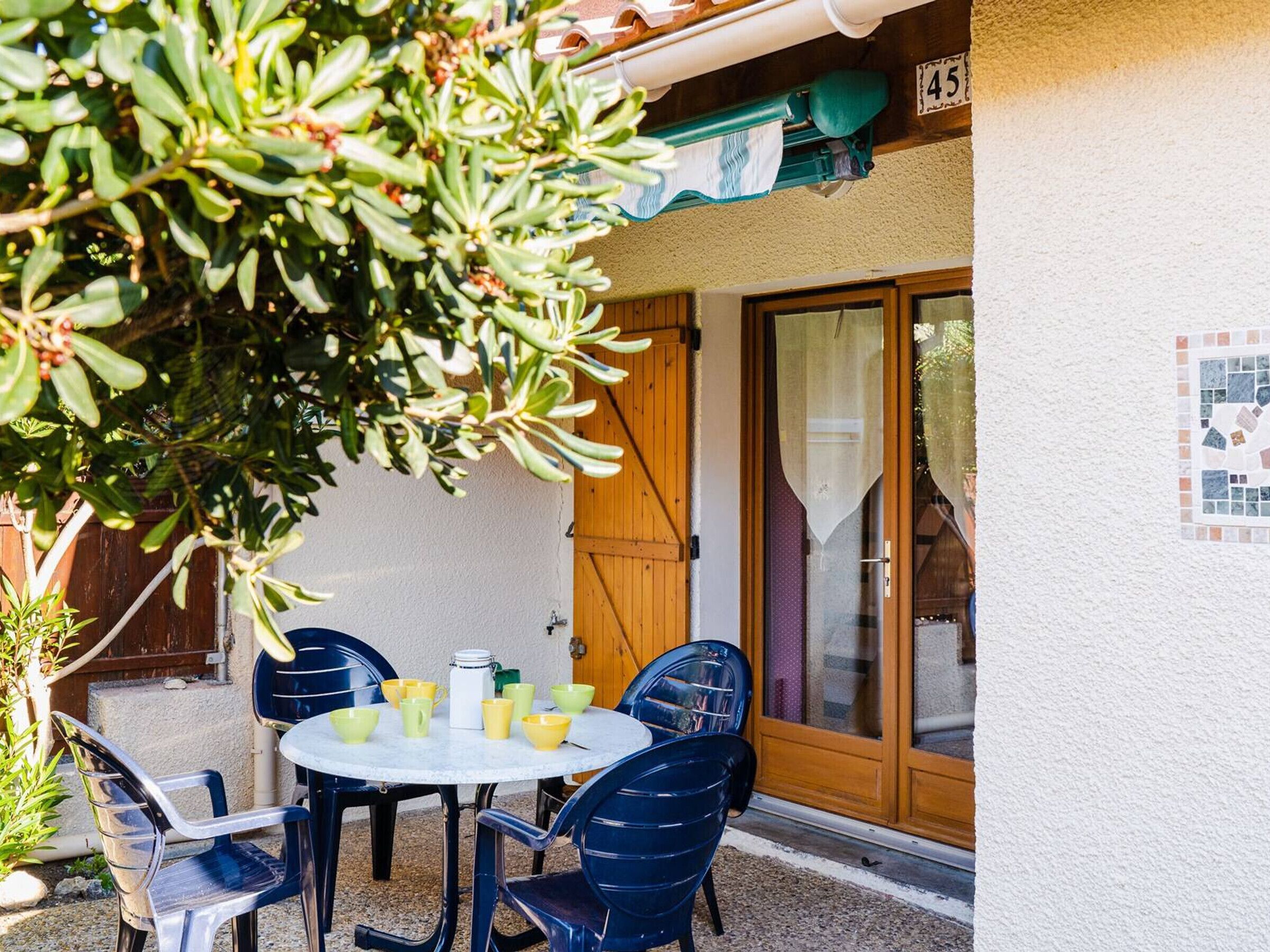 A patio with a round table and chairs, a wooden door, and a tiled wall.