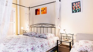 A four-poster bed with a canopy, a bedside table with a lamp, and a wall-mounted picture. - Cozy Villa Studio with Mezzanine, Terrace, and Parking near Narbonne-Plage (Narbonne-Narbonne Plage-Narbonne Plage)