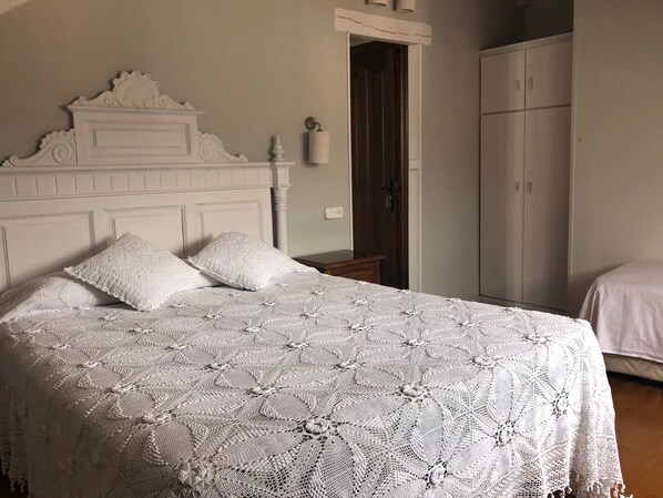 Un dormitorio con una cama grande, un armario y una puerta que da a otra habitación.