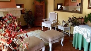 A room with a white chair, a small table, a mirror, and a green tablecloth.